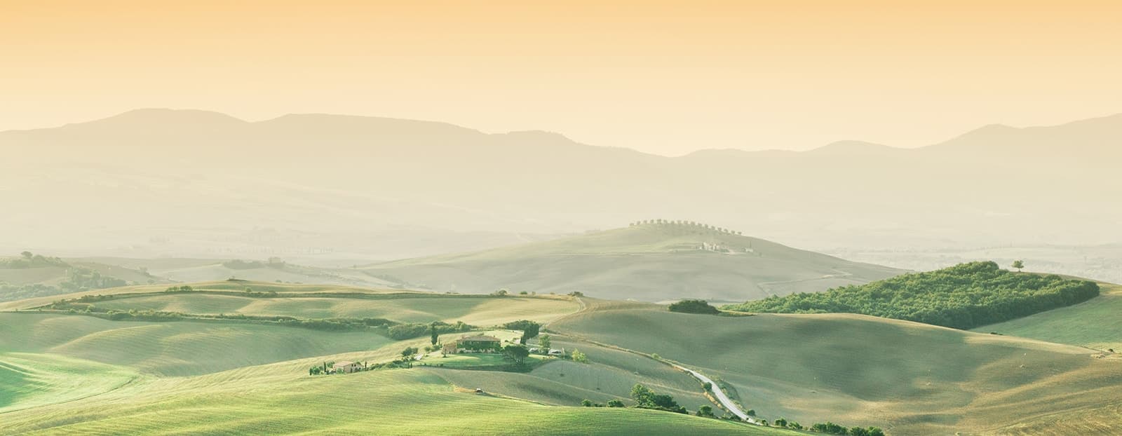A serene landscape of rolling green hills under a golden sky, with a small farm nestled among the fields.